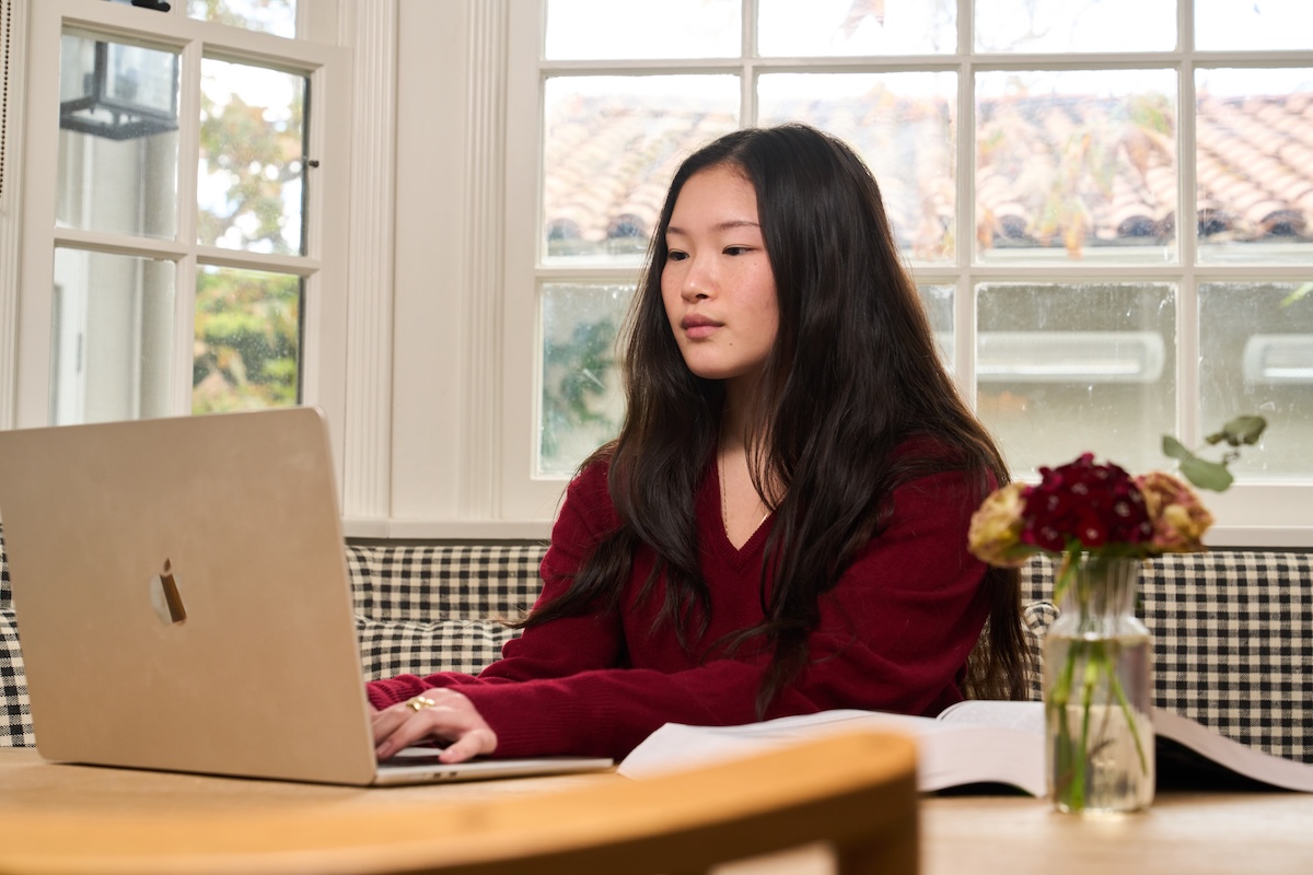High school student working on college application activities list on laptop